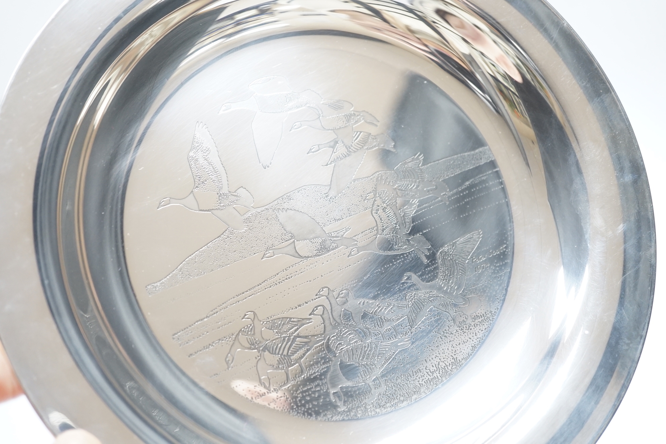 A boxed silver Peter Scott Christmas plate, 1974, depicting etched birds in flight, John Pinches, London 1974. Diameter 20.5cm, 5.9oz.